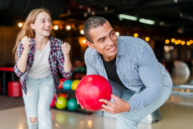 Joven mujer y hombre de pie en un club de bolos