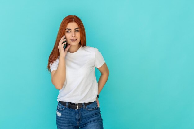 Joven mujer de jengibre hablando de teléfono de pie sobre turquesa