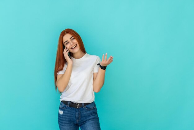 Joven mujer de jengibre hablando de teléfono de pie sobre turquesa