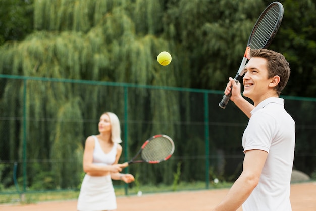 Joven y mujer jugando tenis