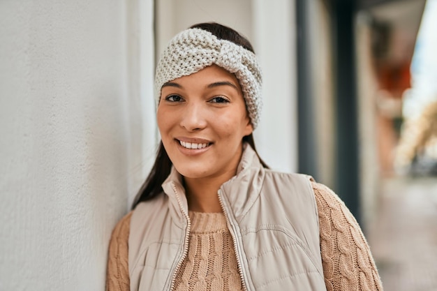 Joven mujer latina sonriendo feliz de pie en la ciudad