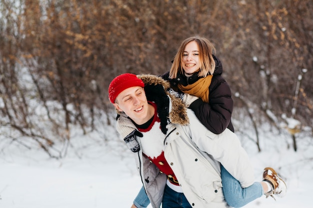 Joven mujer llevando en la espalda en el bosque de invierno