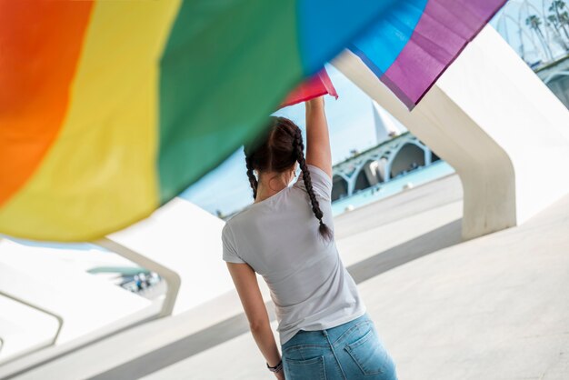 Joven mujer manteniendo la bandera del arco iris