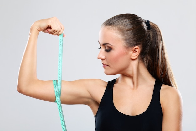 Foto gratuita joven mujer midiendo su brazo