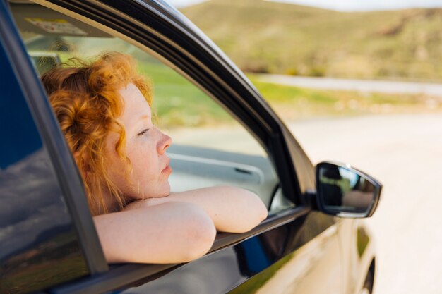 Joven mujer mirando por la ventana del coche