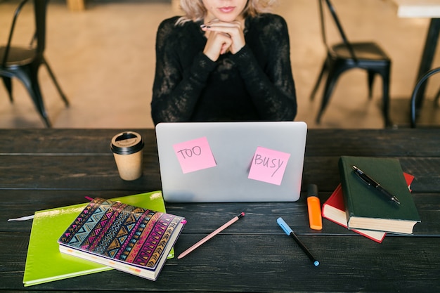 Foto gratuita joven mujer muy ocupada trabajando en la computadora portátil, pegatinas de papel ocupadas, consentimiento, estudiante en la sala de clase, vista superior en la mesa con papelería, no molestar