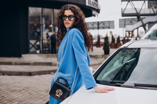 Joven mujer de negocios feliz saliendo de su coche