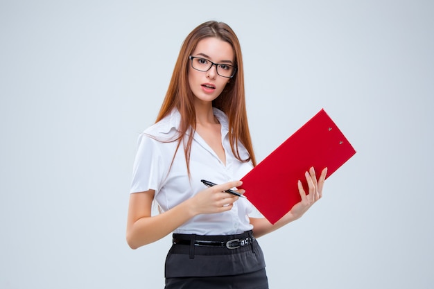 La joven mujer de negocios con lápiz y tableta para notas en gris