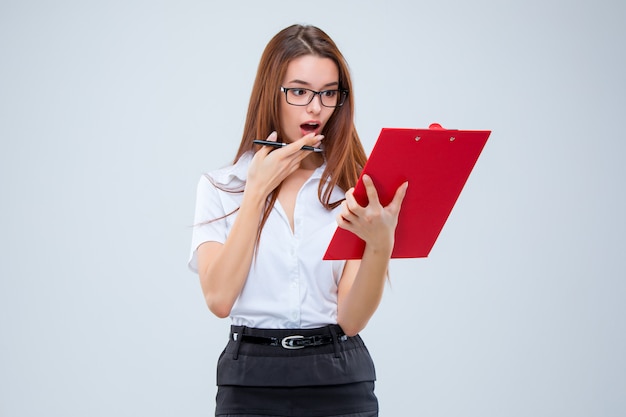 Foto gratuita la joven mujer de negocios con lápiz y tableta para notas en la pared gris