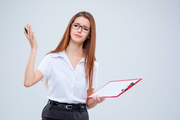 La joven mujer de negocios con lápiz y tableta para notas sobre gris