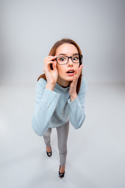 La joven mujer de negocios en la pared gris