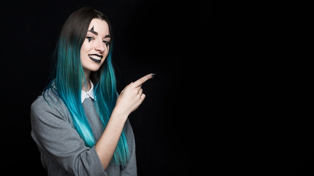 Joven mujer de pelo azul apuntando con el dedo a un lado