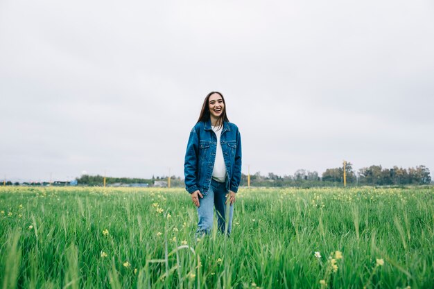 Joven mujer permaneciendo en el campo y riendo