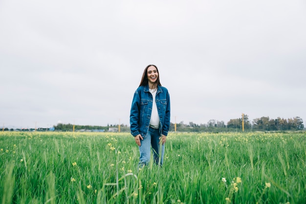 Joven mujer permaneciendo en el campo y riendo