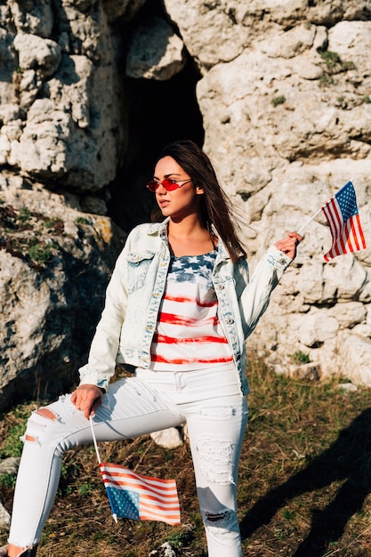 Foto gratuita joven mujer de pie en las montañas con banderas americanas