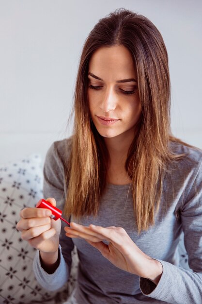 Joven mujer pintando las uñas