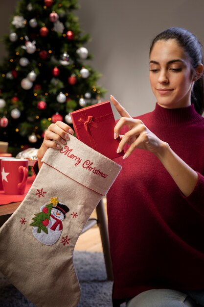 Joven mujer poniendo regalos en medias gigantes