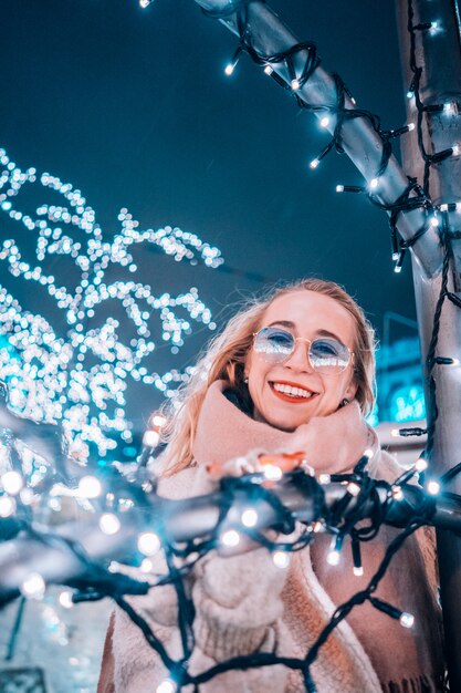 Joven mujer posando en la calle con árboles iluminados