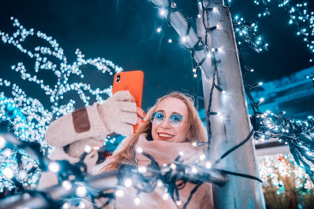 Joven mujer posando en la calle con árboles iluminados