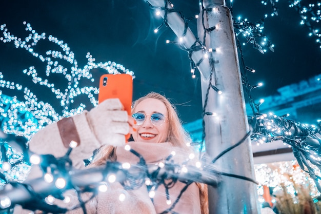 Joven mujer posando en la calle con árboles iluminados