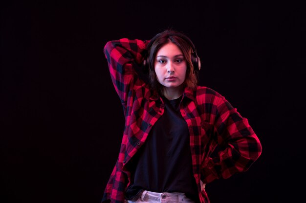 Joven mujer posando con camisa roja y negra a cuadros con auriculares