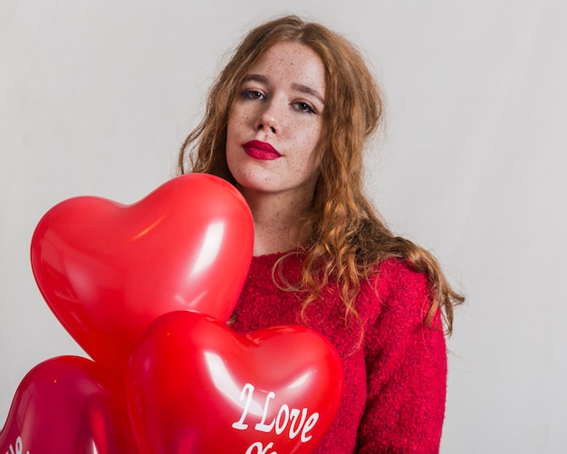 Joven mujer posando con globos de corazón