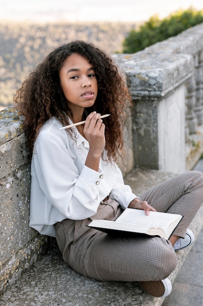 Joven mujer posando mientras sostiene un libro