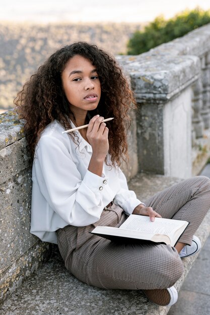 Joven mujer posando mientras sostiene un libro