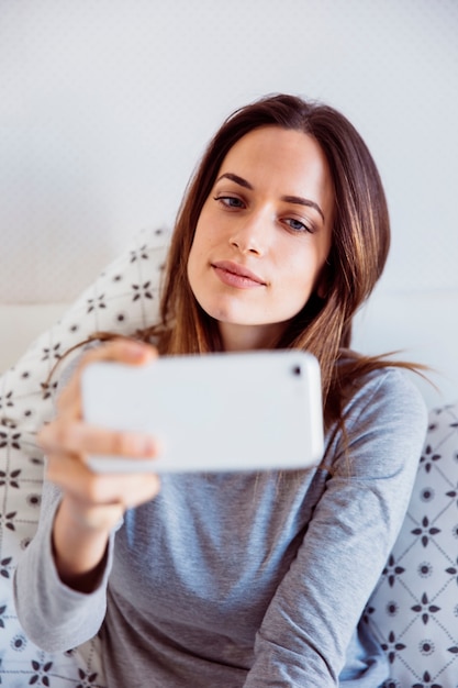 Joven mujer posando para selfie en la cama