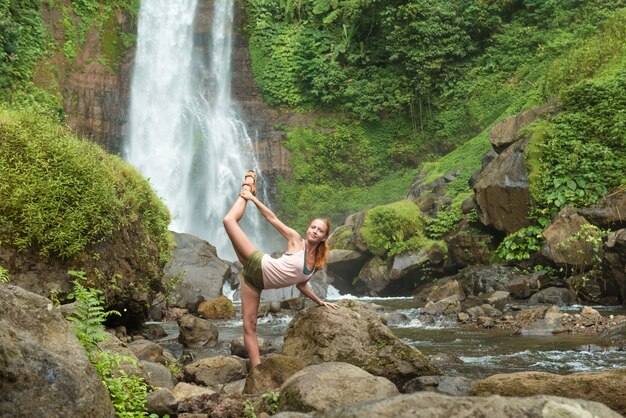 Joven, mujer, practicar, yoga, cascada