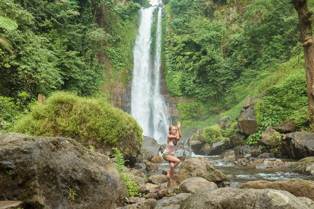 Joven, mujer, practicar, yoga, cascada