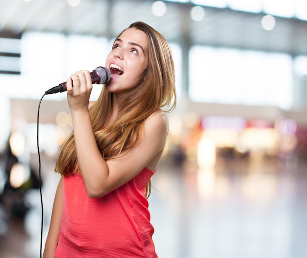 joven mujer que canta con un micrófono en el fondo blanco