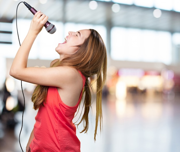 joven mujer que canta con un micrófono en el fondo blanco