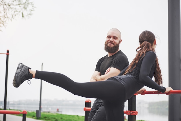 Joven y mujer realizan ejercicios y estrías antes de hacer deporte