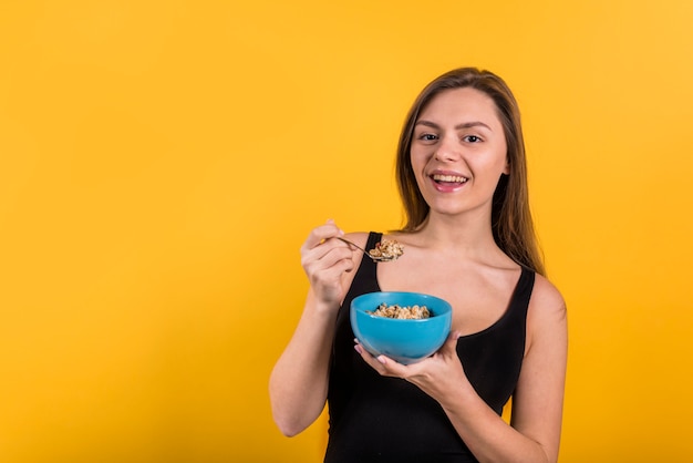 Joven mujer riendo con cuchara y tazón de copos