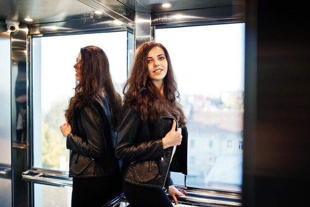 Joven mujer rizada con chaqueta de cuero en el ascensor