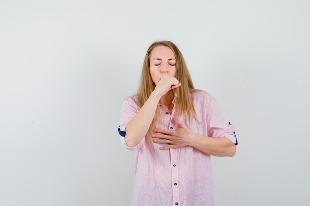 Foto gratuita joven mujer rubia en una camisa rosa casual tosiendo