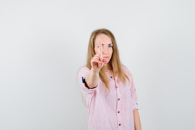 Joven mujer rubia con una camisa rosa casual