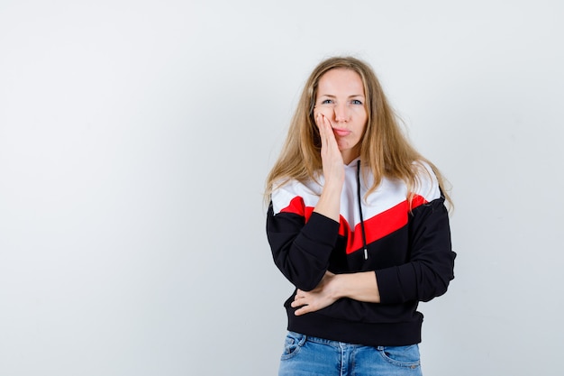 Joven mujer rubia en una chaqueta y jeans