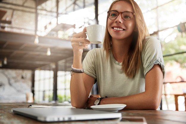 Joven mujer rubia con gafas en el café