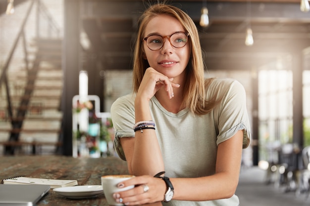 Joven mujer rubia con gafas en el café