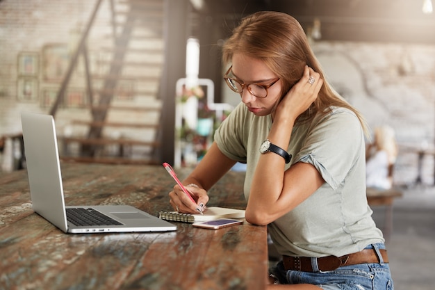 Joven mujer rubia con gafas en el café