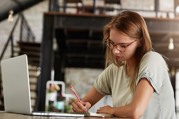 Joven mujer rubia con gafas en el café