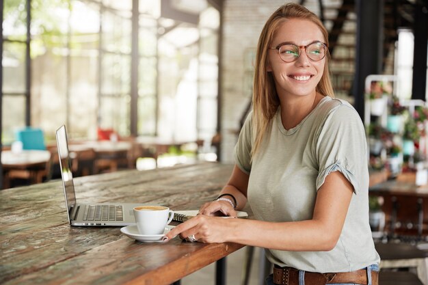 Joven mujer rubia con gafas en el café