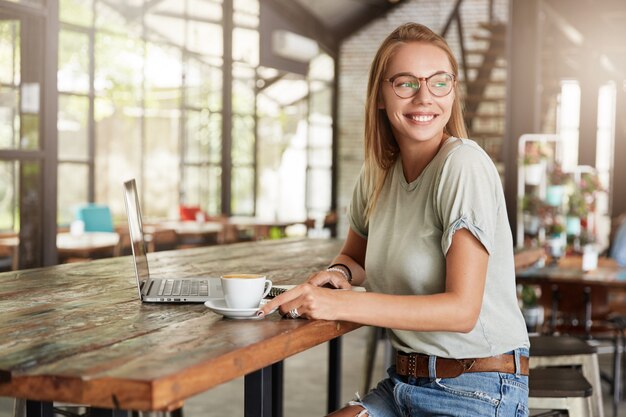 Joven mujer rubia con gafas en el café