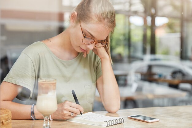 Joven mujer rubia con gafas en el café