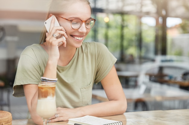 Joven mujer rubia con gafas en el café