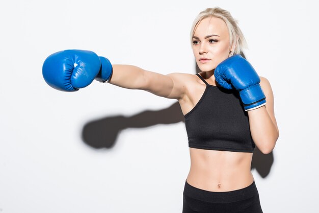 Joven mujer rubia con guantes de boxeo azules sobre blanco