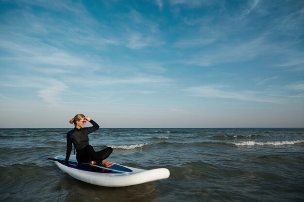 Joven mujer rubia en paddleboard en el mar