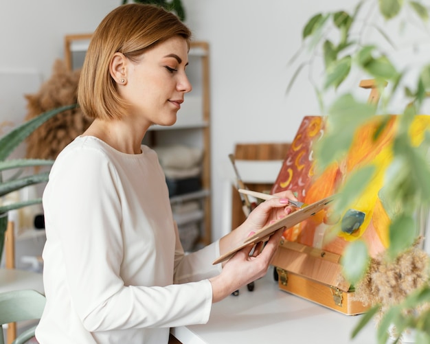 Joven mujer rubia pintando con acrílicos